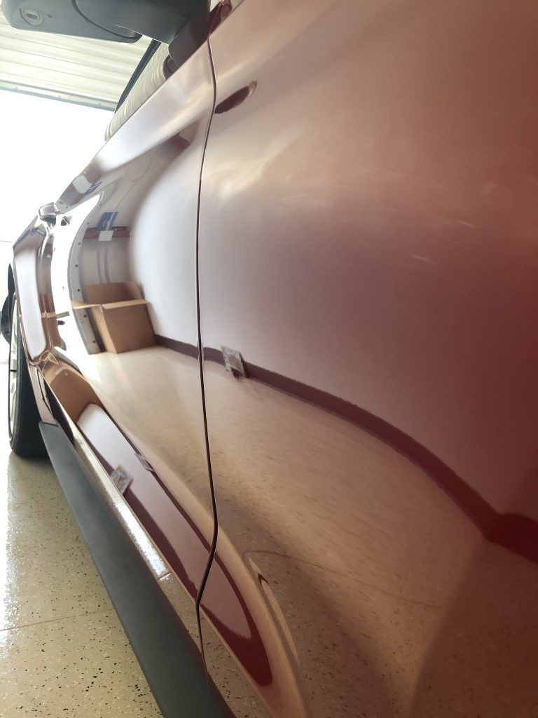 A red car is parked in a garage with the door open