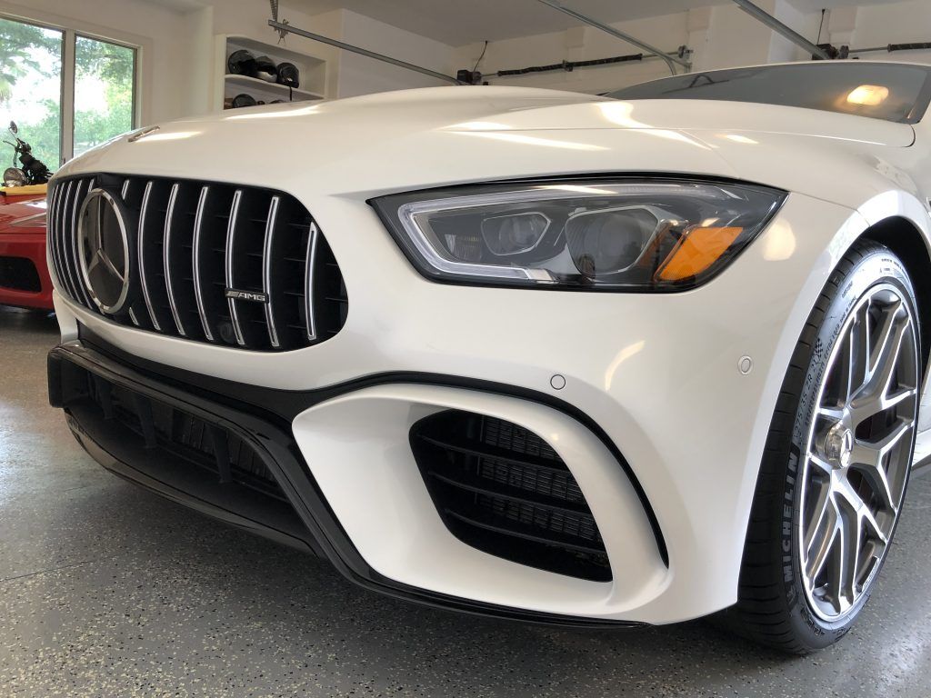 A white mercedes benz is parked in a garage.