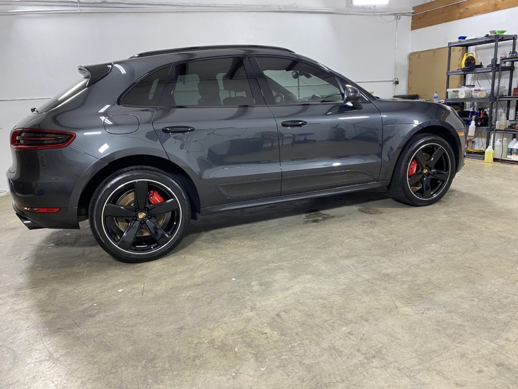 A gray porsche macan is parked in a garage.