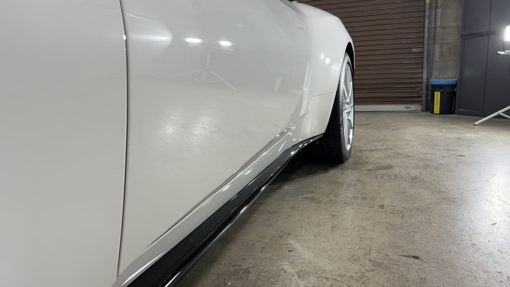 A white car is parked in a garage next to a garage door.