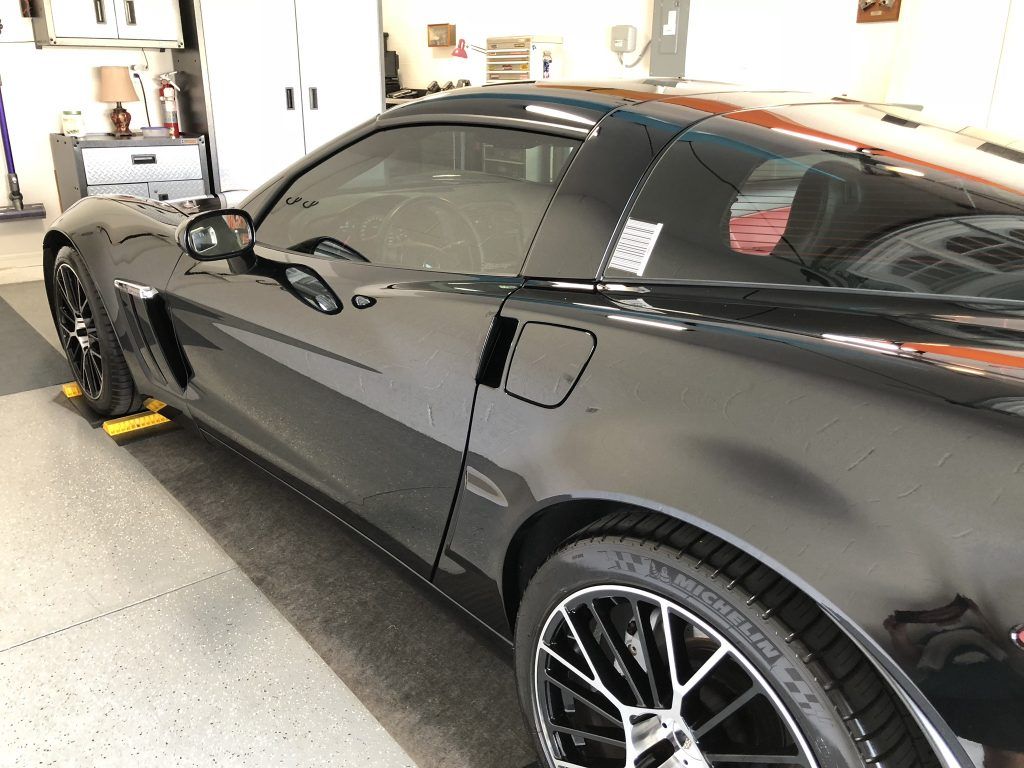 A black sports car is parked in a garage.