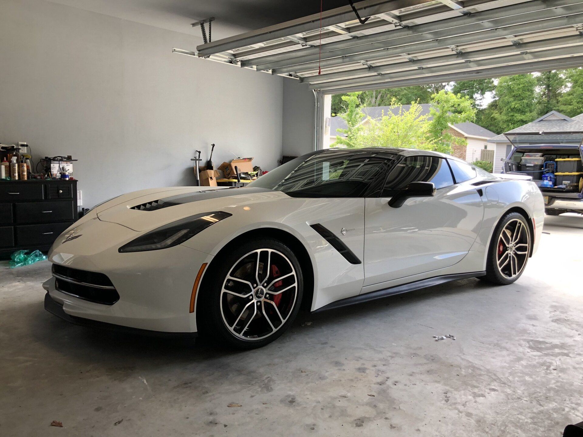 A white corvette is parked in a garage.