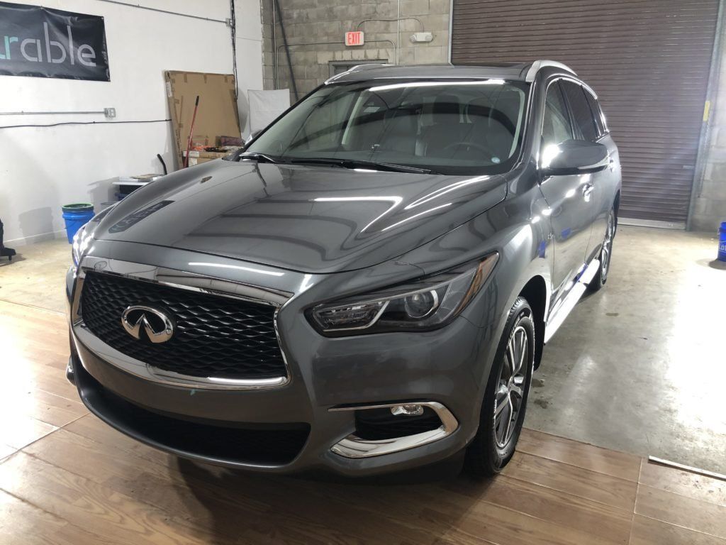 A gray infiniti qx60 is parked in a garage.
