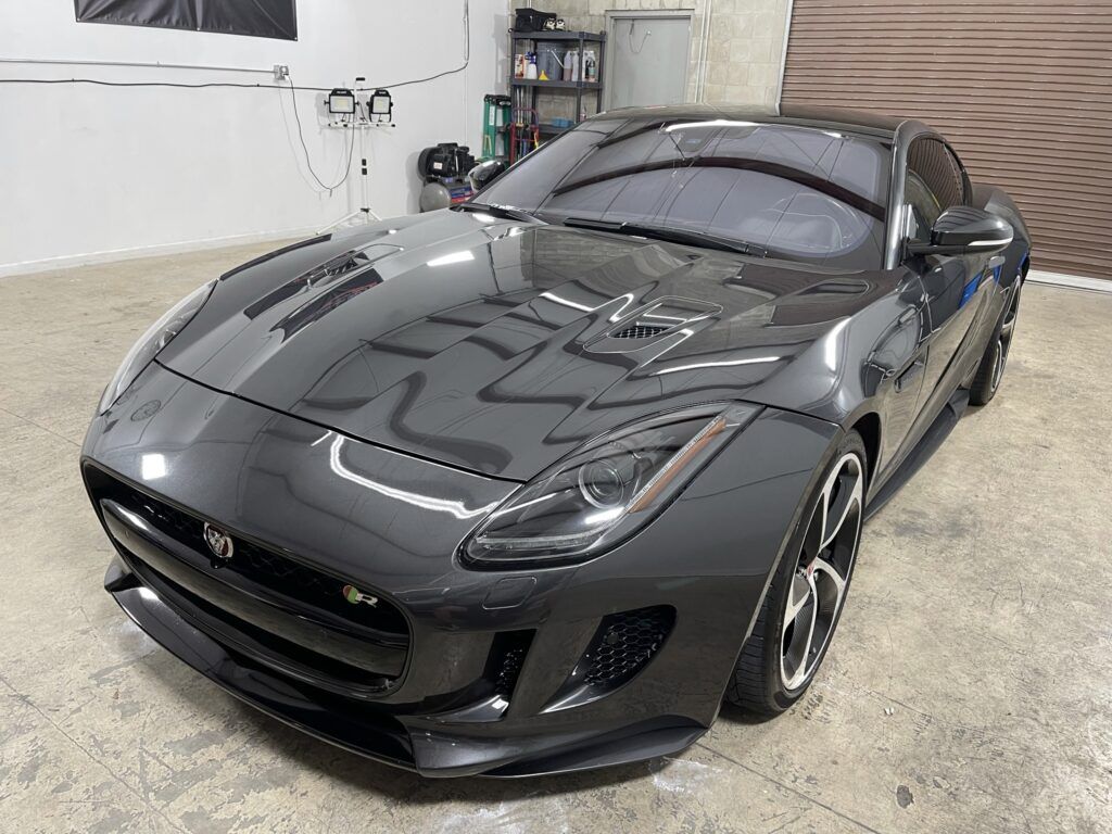 A black sports car is parked in a garage.