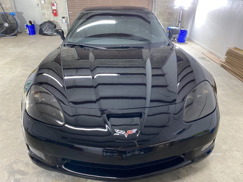 A black corvette is parked in a garage.