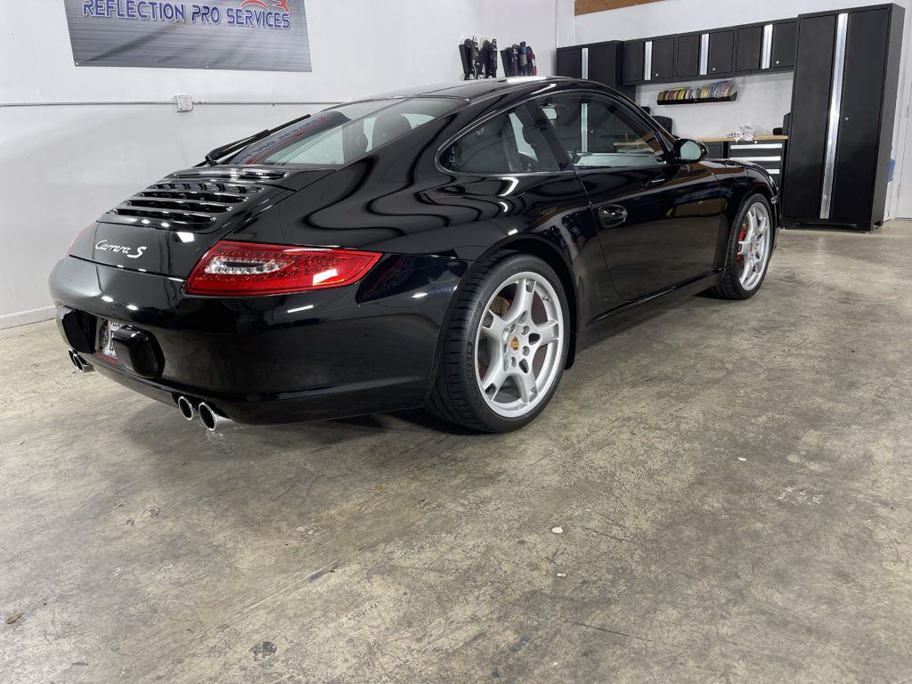 A black porsche 911 is parked in a garage.