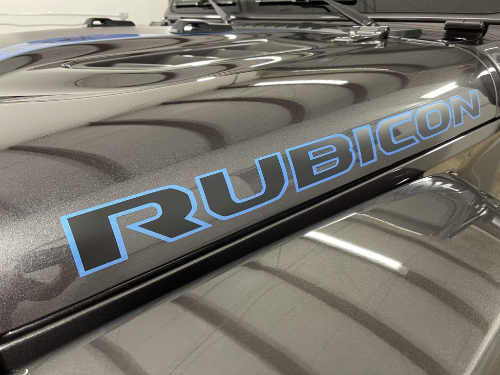 A black jeep with a blue rubicon sticker on the hood