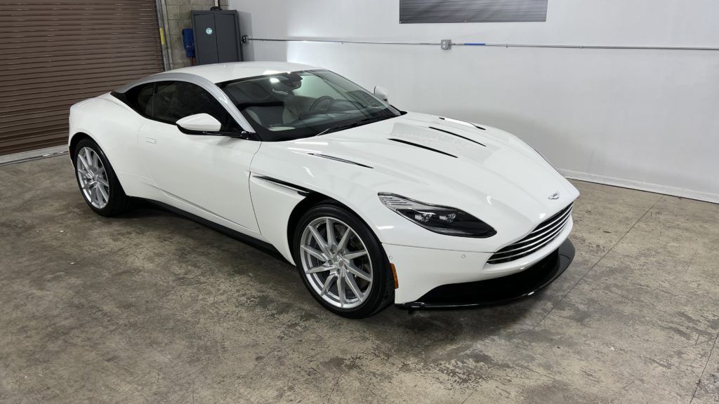 A white aston martin db11 is parked in a garage.