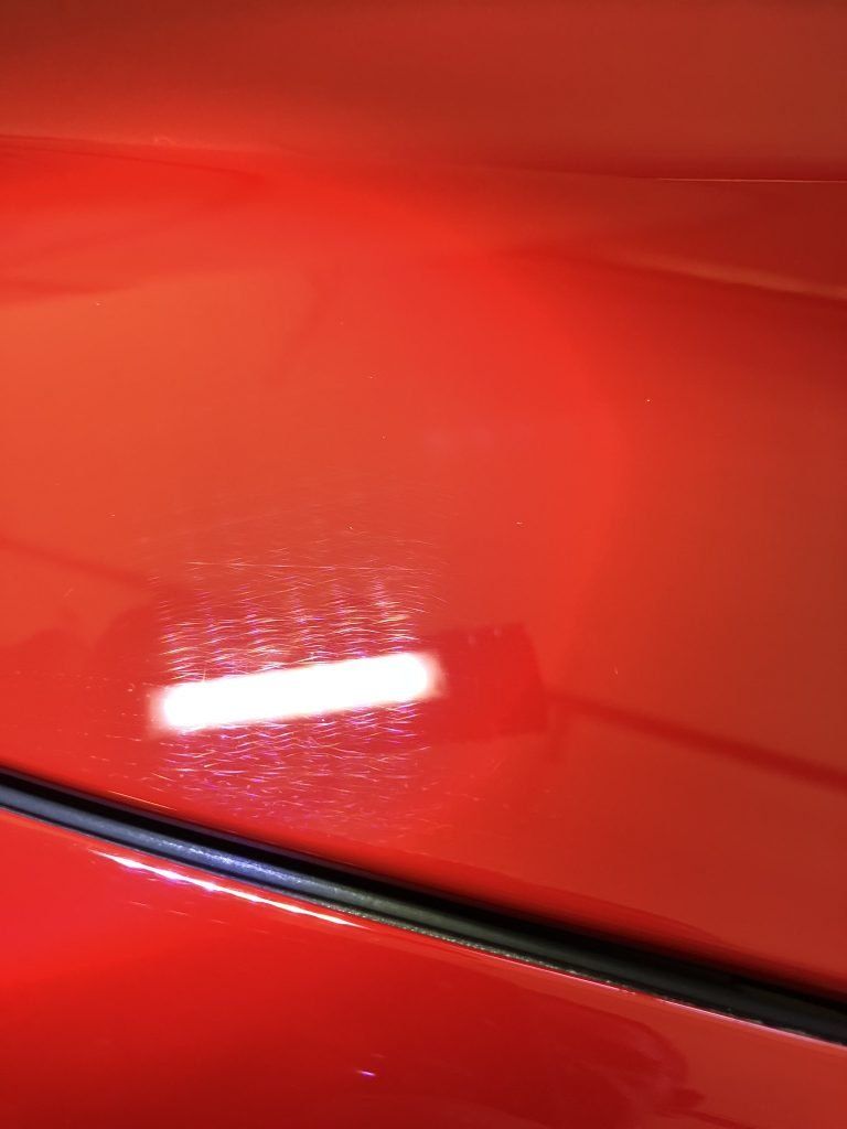 A close up of a red car with a light shining on it.