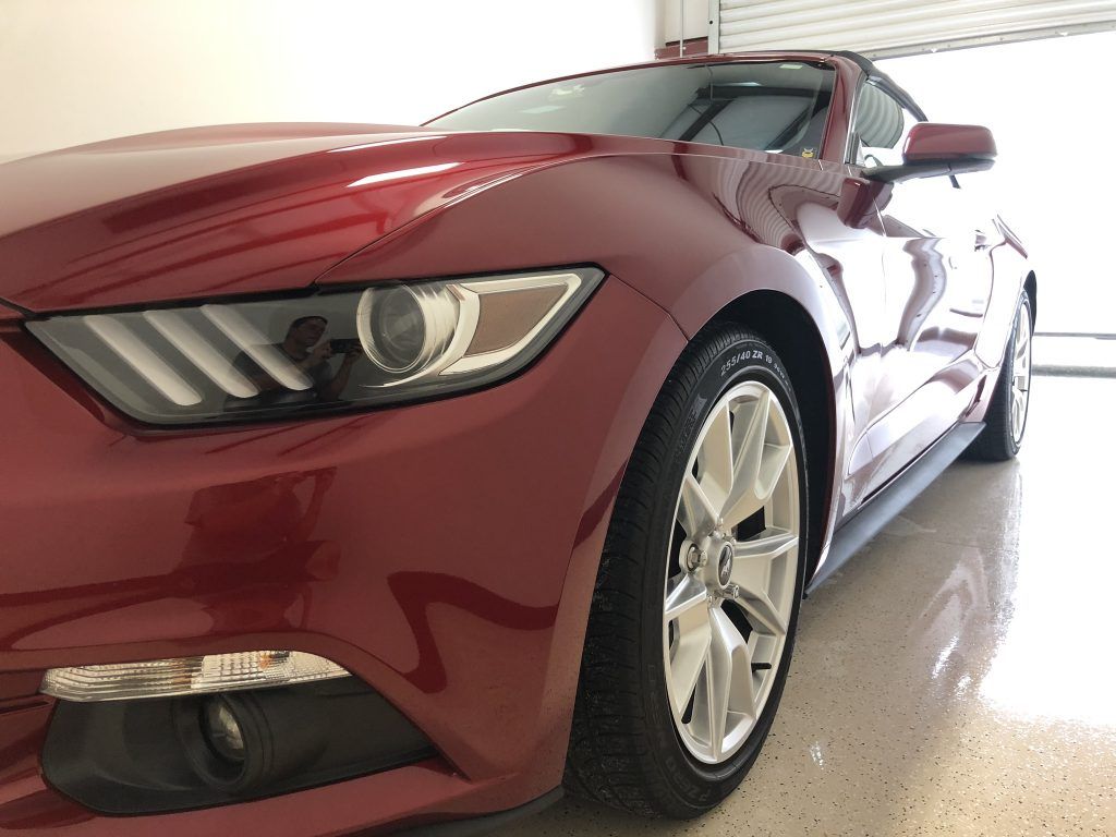 A red ford mustang is parked in a garage.