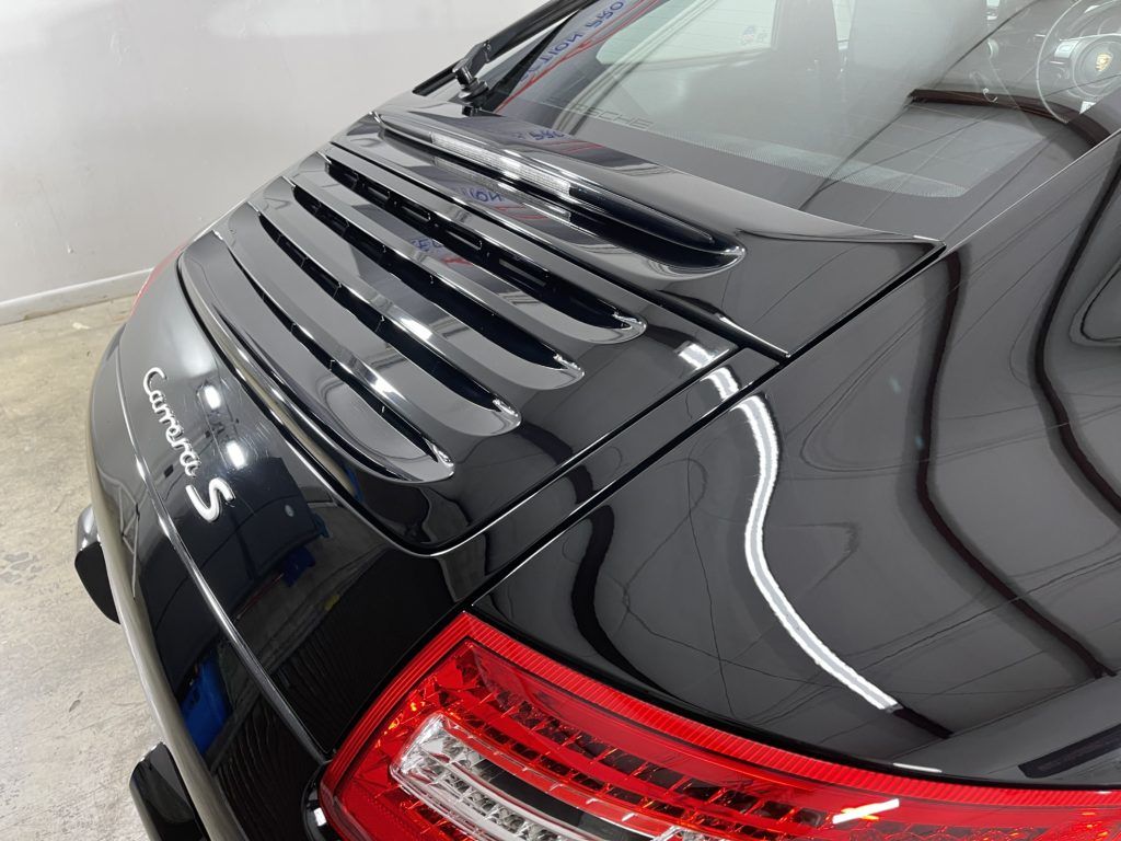 A black porsche 911 turbo s is parked in a garage.