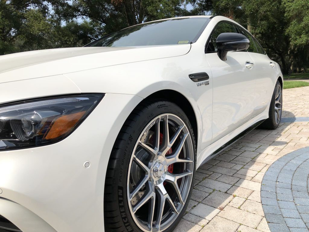 A white sports car is parked on a brick driveway.