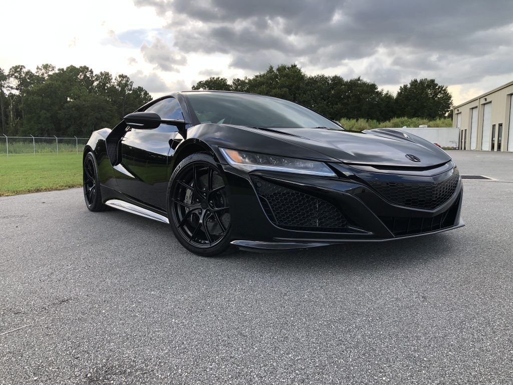 A black sports car is parked on the side of the road.