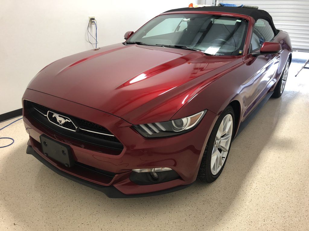 A red ford mustang convertible is parked in a garage.