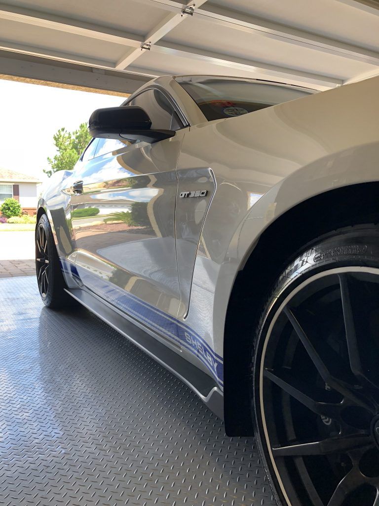 A white mustang is parked in a garage.