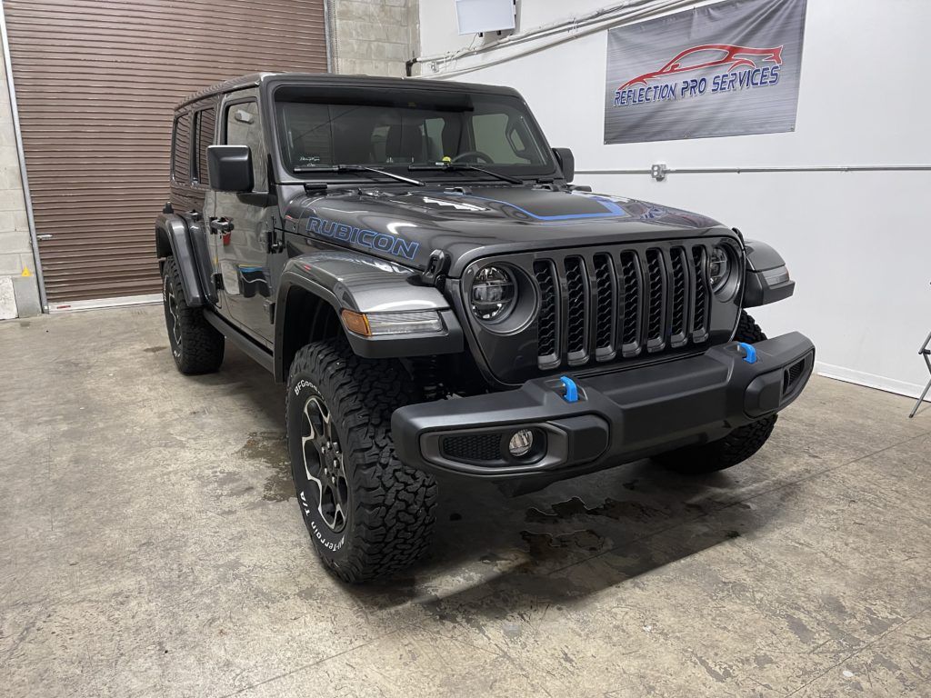 A jeep wrangler is parked in a garage next to a flag.