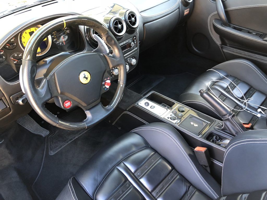 The interior of a ferrari sports car with black seats and a steering wheel.