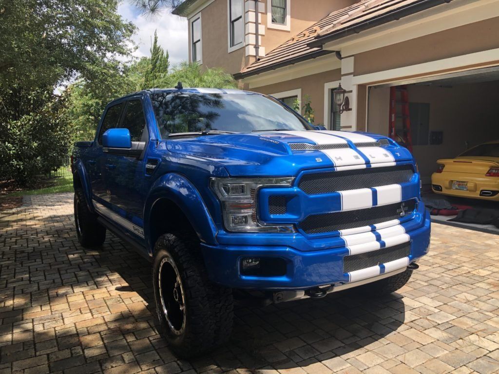 A blue truck is parked in front of a house in a driveway.