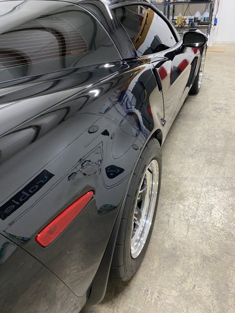 A black sports car is parked in a garage.
