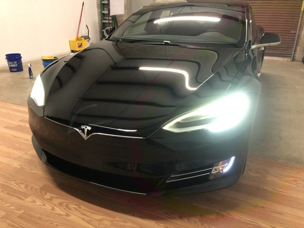 A black tesla model s is parked in a garage.