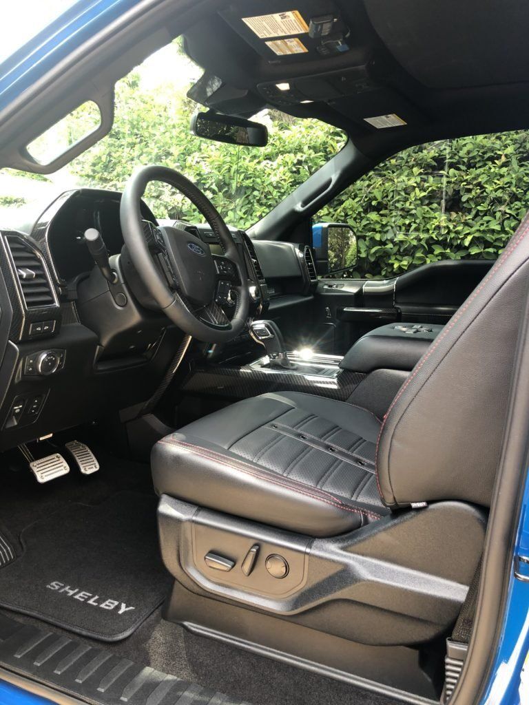 The interior of a blue truck with black seats and a steering wheel.