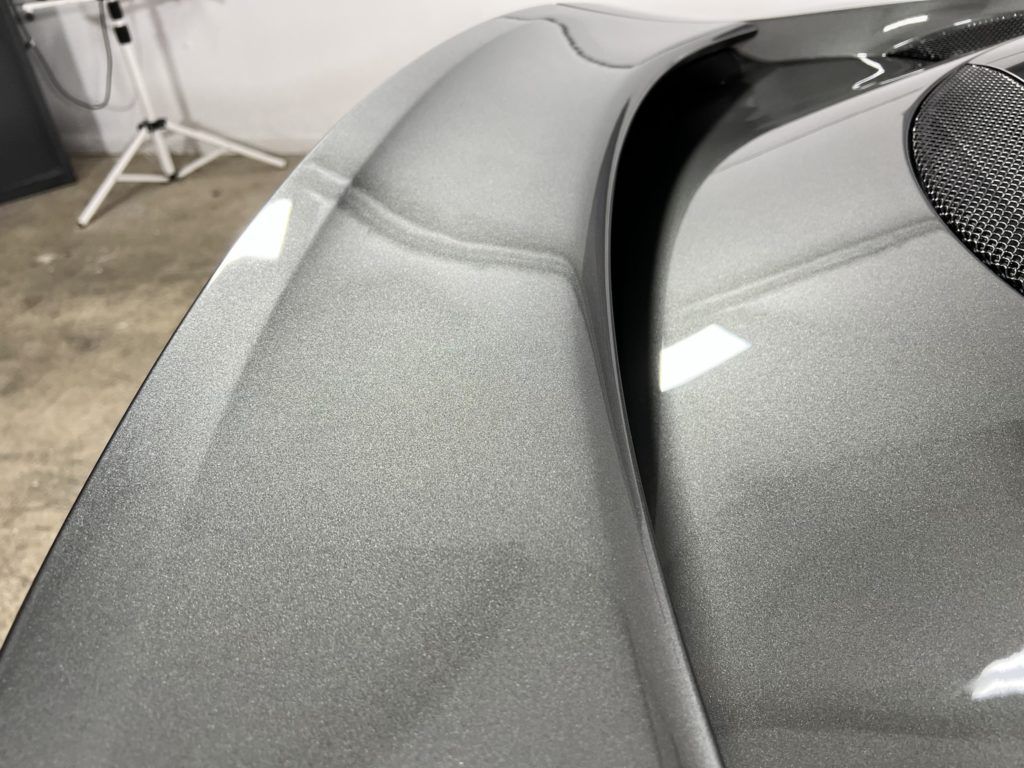 A close up of a gray car 's hood in a garage.