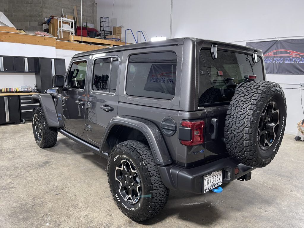 A gray jeep wrangler is parked in a garage.