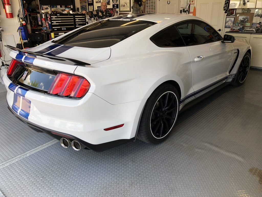 A white ford mustang is parked in a garage.