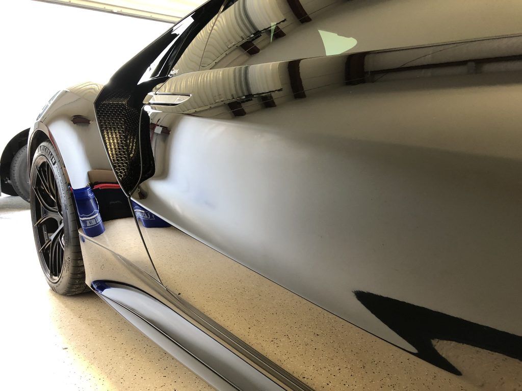 A car is parked in a garage with a black arrow on the side