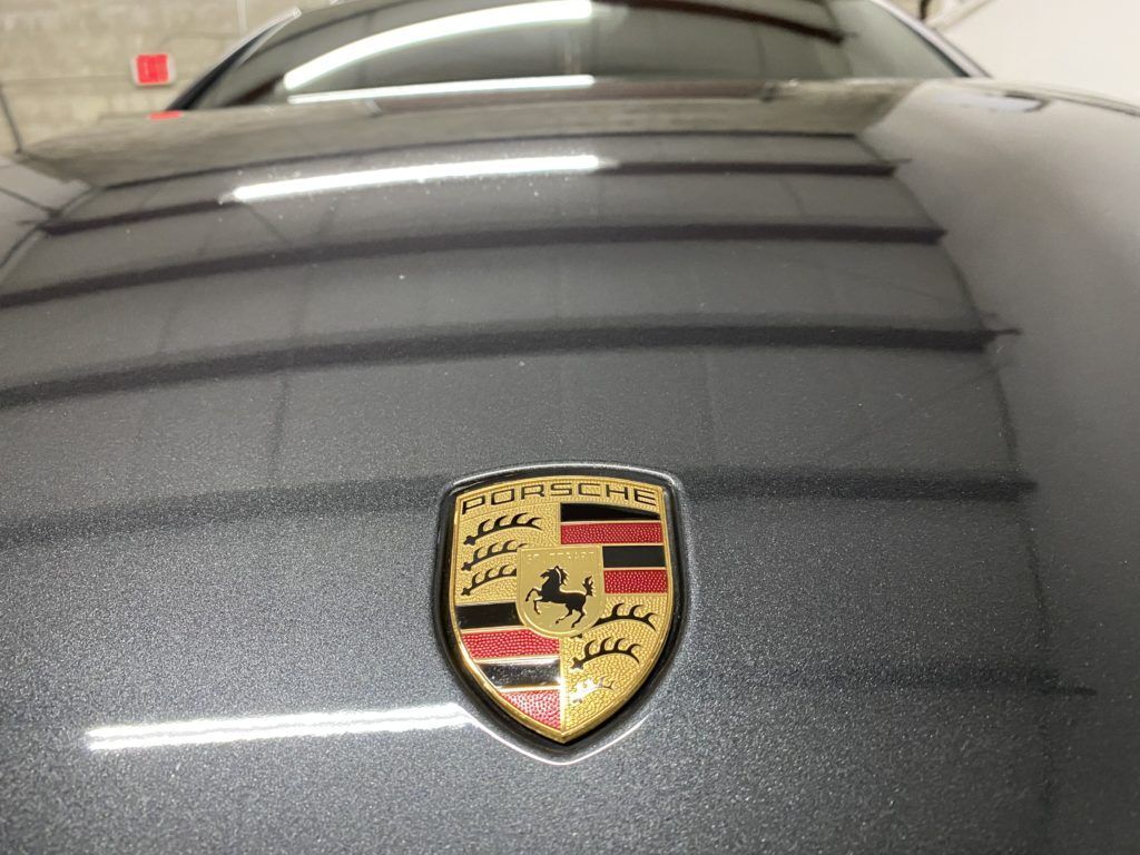 A close up of a porsche emblem on the hood of a car