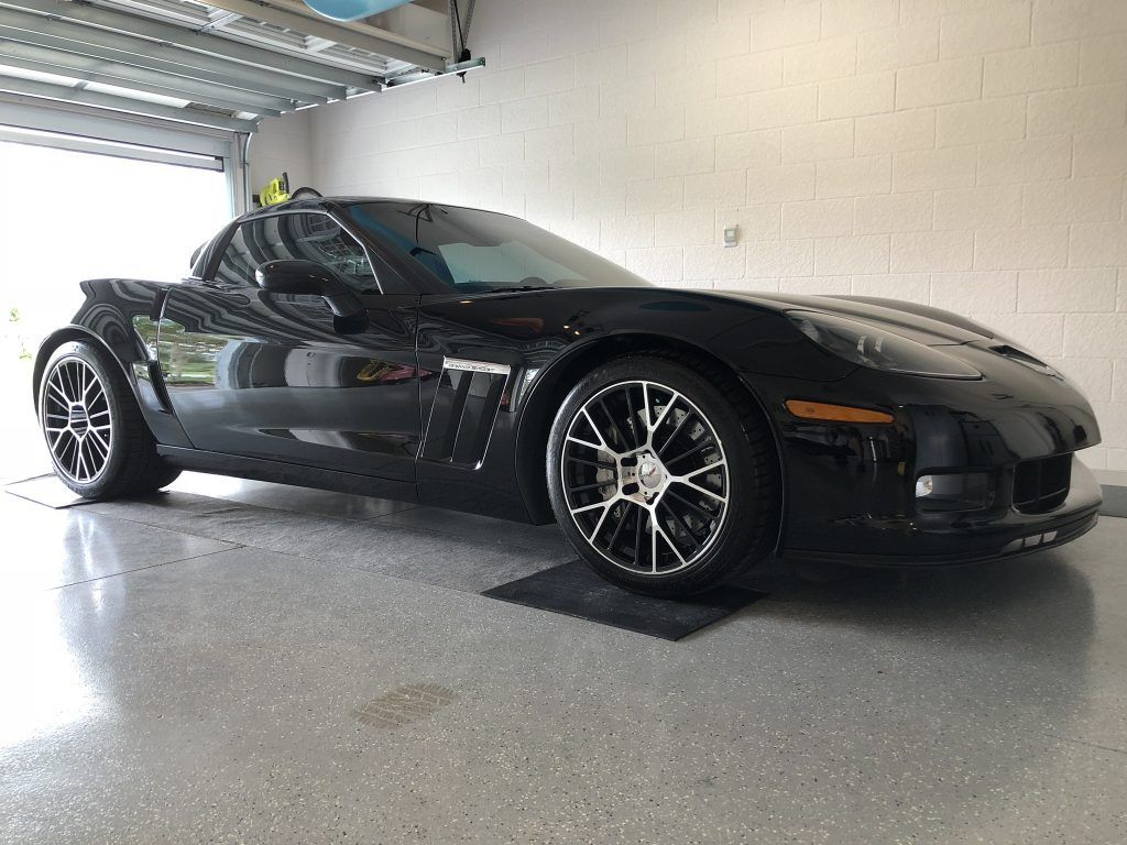 A black sports car is parked in a garage.