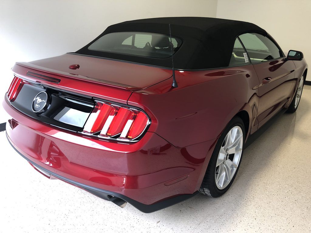 A red mustang convertible is parked in a garage.