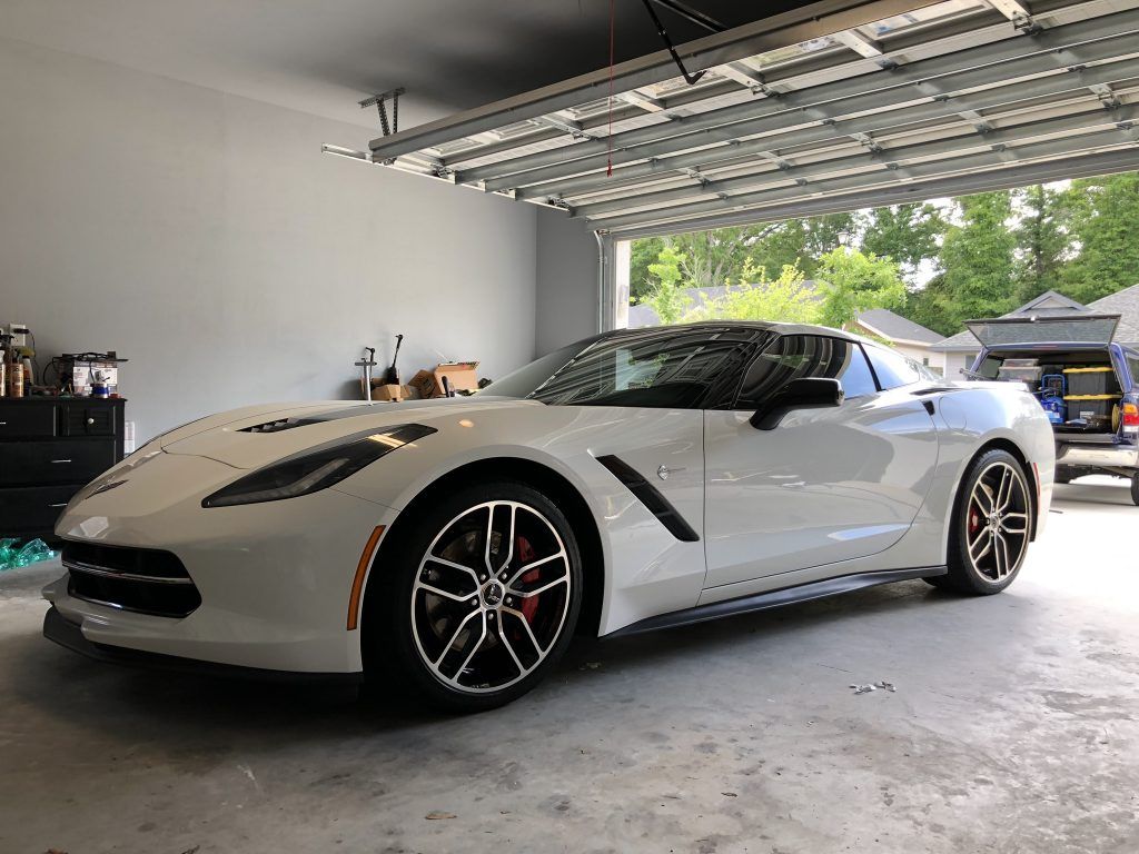 A white corvette is parked in a garage.