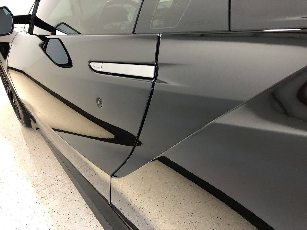 A black car is parked in a garage with the door open