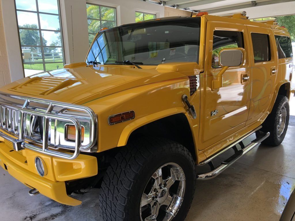 A yellow hummer h2 is parked in a garage.