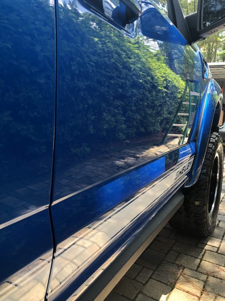 A blue truck is parked on a brick driveway.