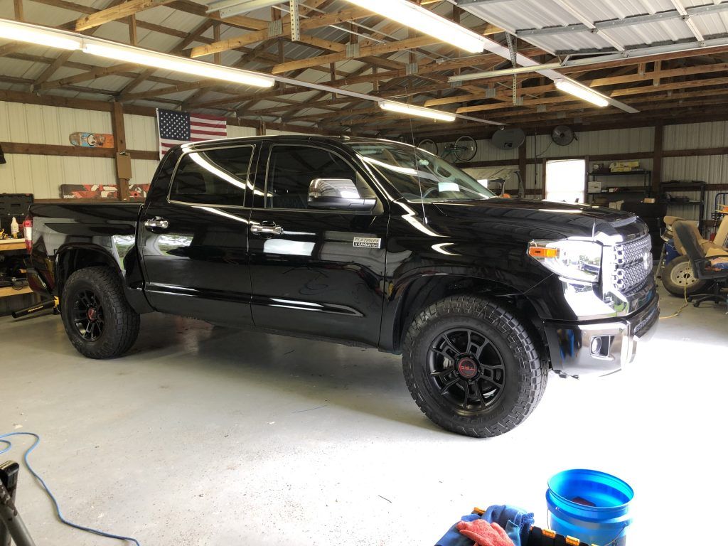 A black toyota tundra is parked in a garage.