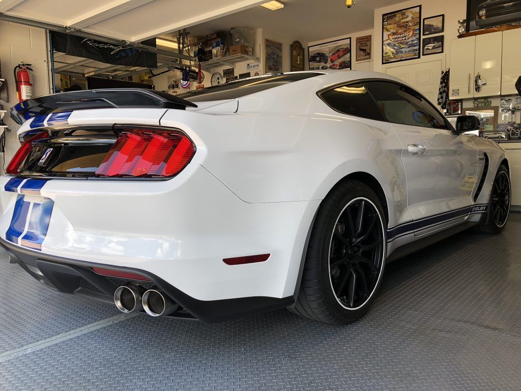 A white ford mustang is parked in a garage.