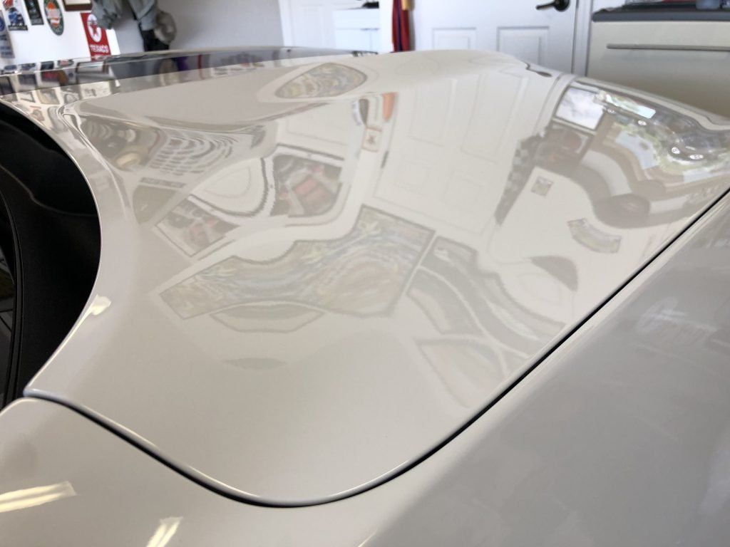 A close up of the hood of a white car in a garage.