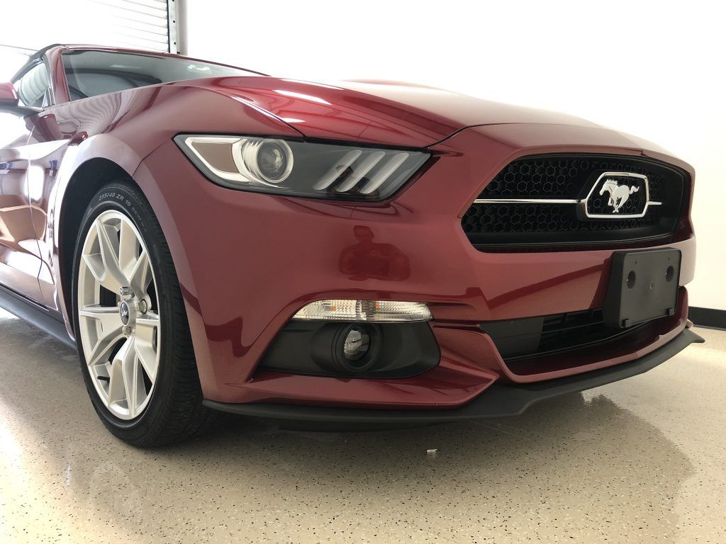 A red ford mustang is parked in a garage.