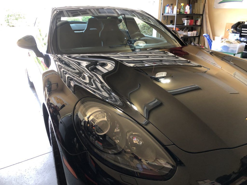 A black sports car is parked in a garage.