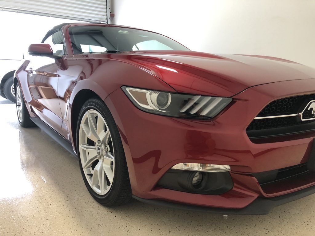 A red ford mustang is parked in a garage.
