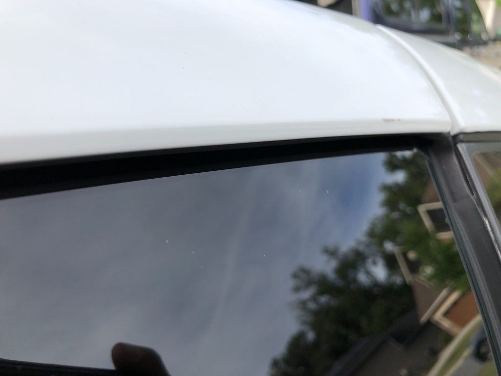 A close up of a car window with a reflection of trees in it