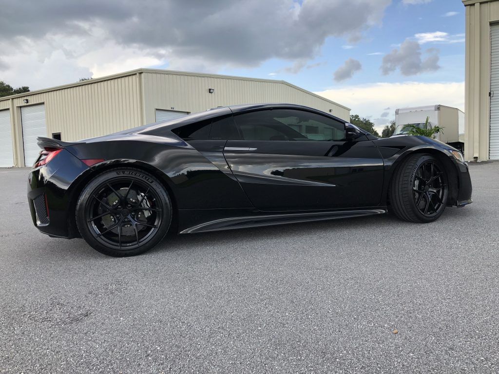 A black sports car is parked in front of a building.