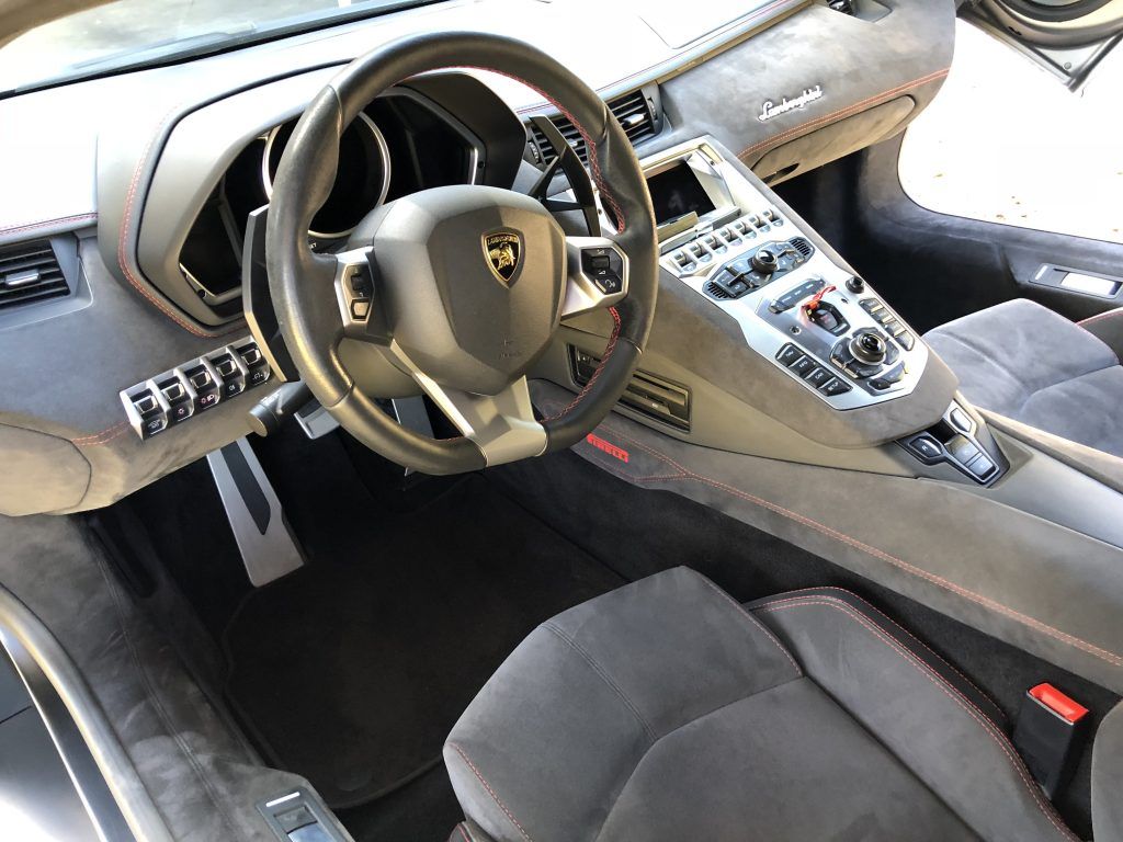 The interior of a lamborghini aventador with a steering wheel and seats.