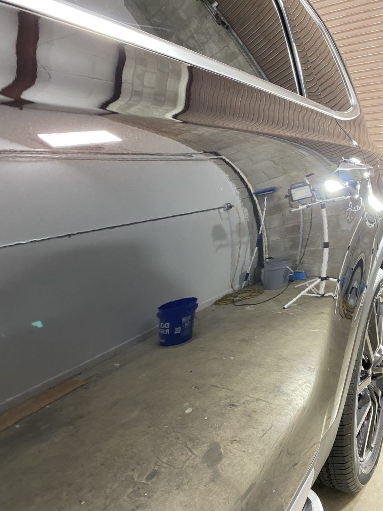 A car is sitting in a garage next to a bucket.