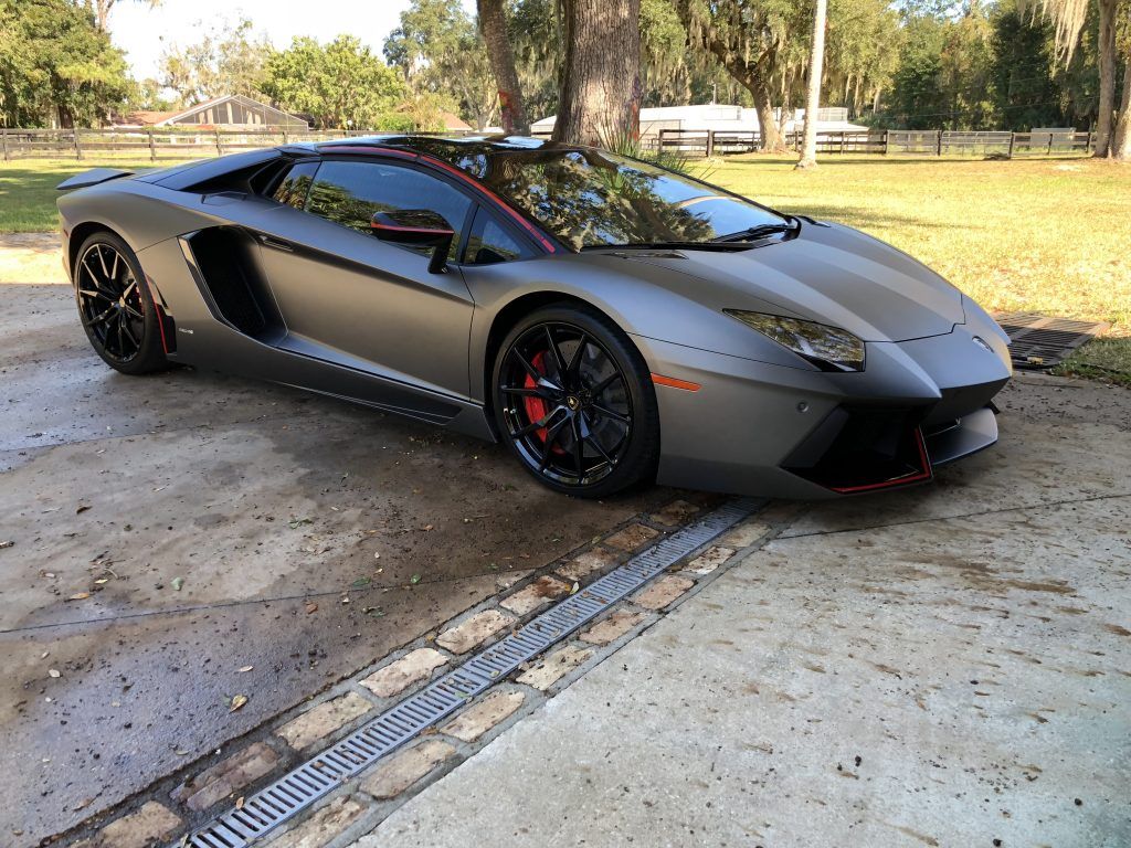 A gray lamborghini aventador is parked in a driveway.
