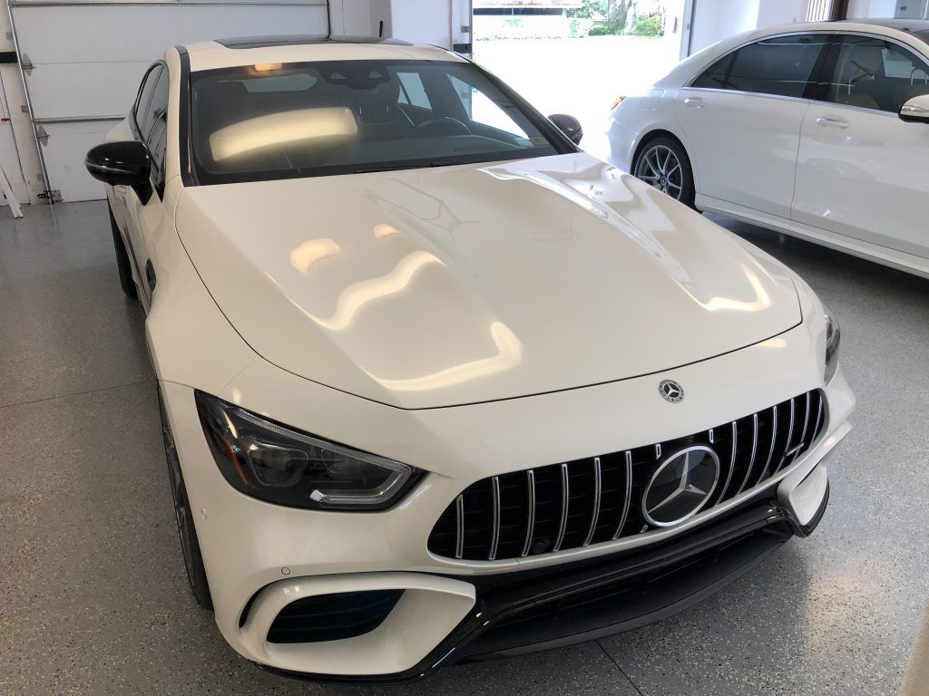 A white mercedes benz is parked in a garage next to another white car.