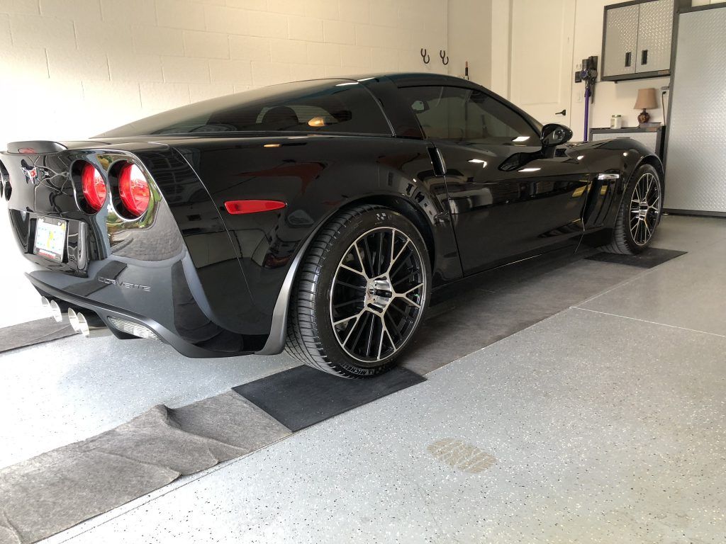 A black sports car is parked in a garage.
