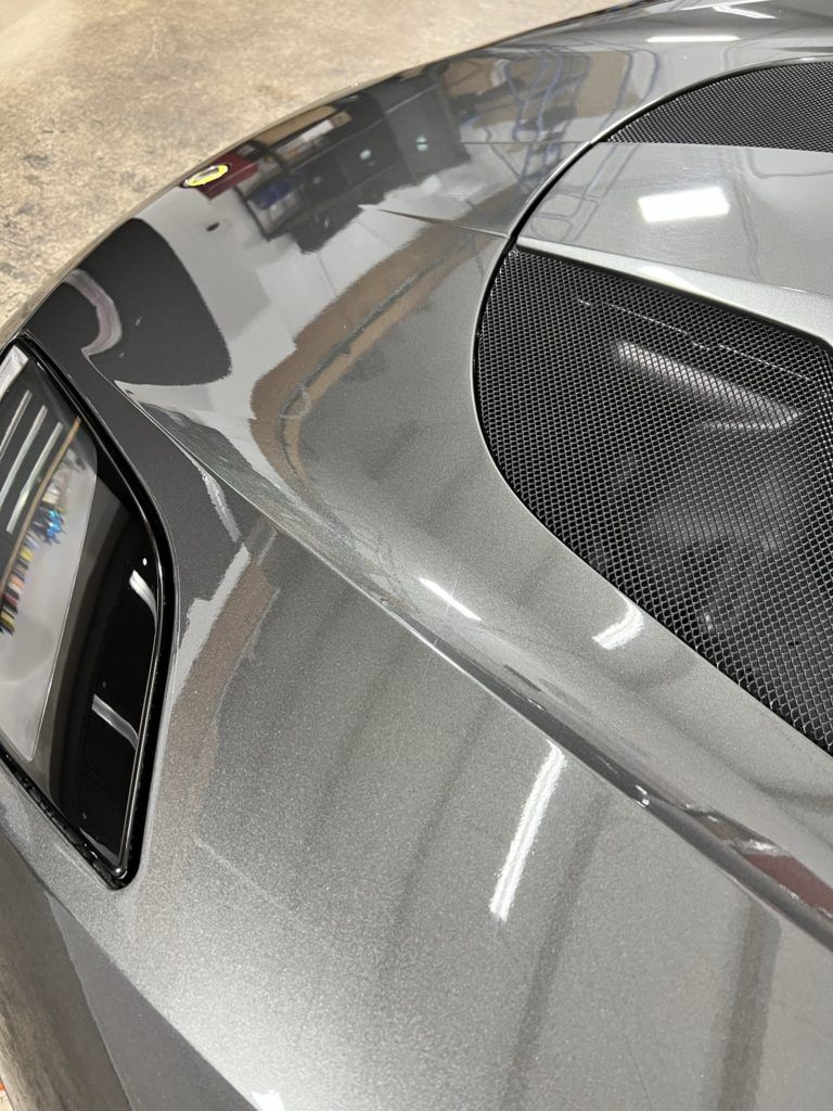 A close up of the hood of a gray sports car.